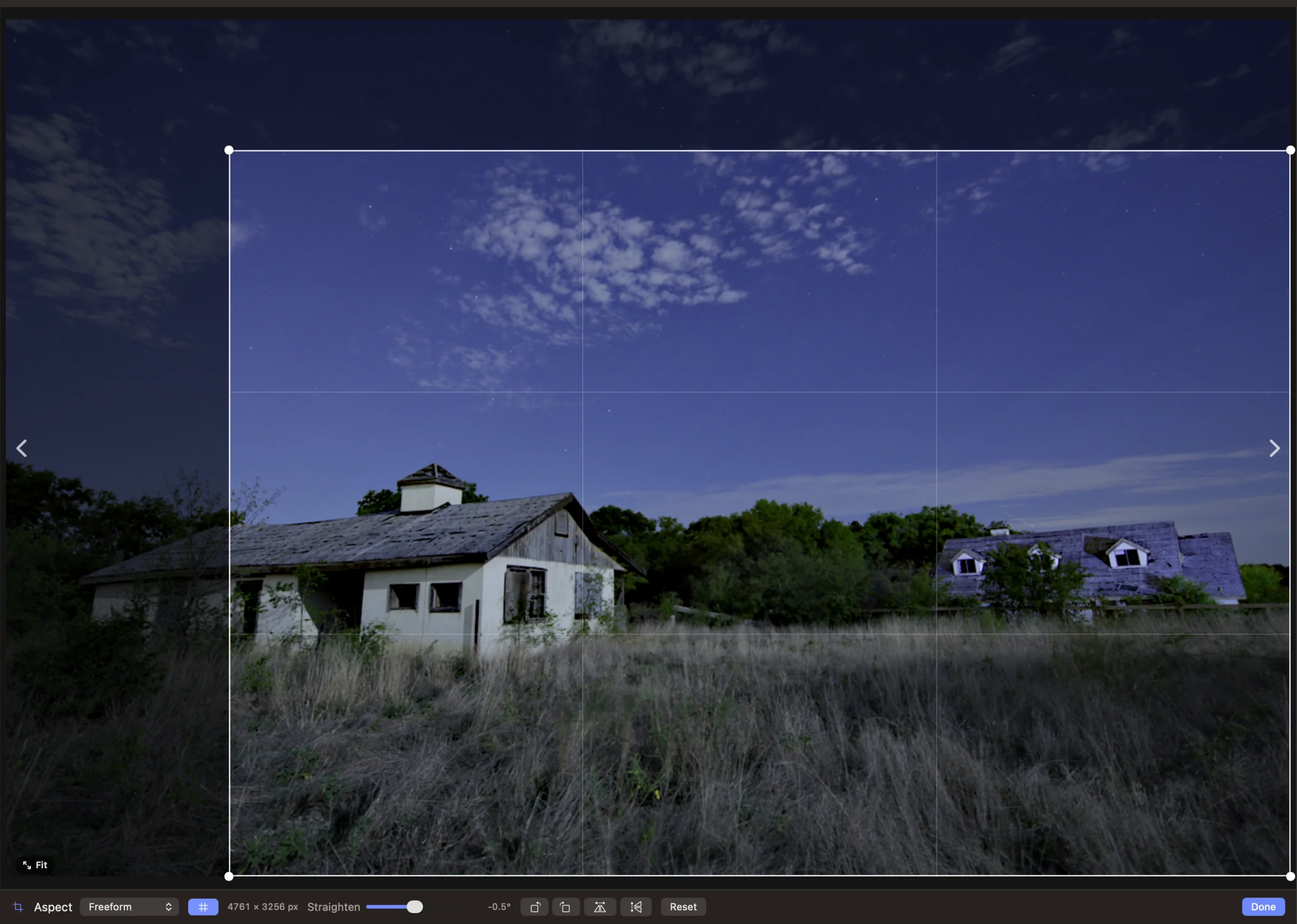 Crop mode over the moonlit farmhouse: a crop rectangle with corner handles and a thirds grid covers most of the frame, the area outside it dimmed but still visible. The bar below shows the Aspect menu set to Freeform, a guides toggle, a readout of 4761 × 3256 px, a Straighten slider at −0.5°, rotate and flip buttons, Reset and Done.