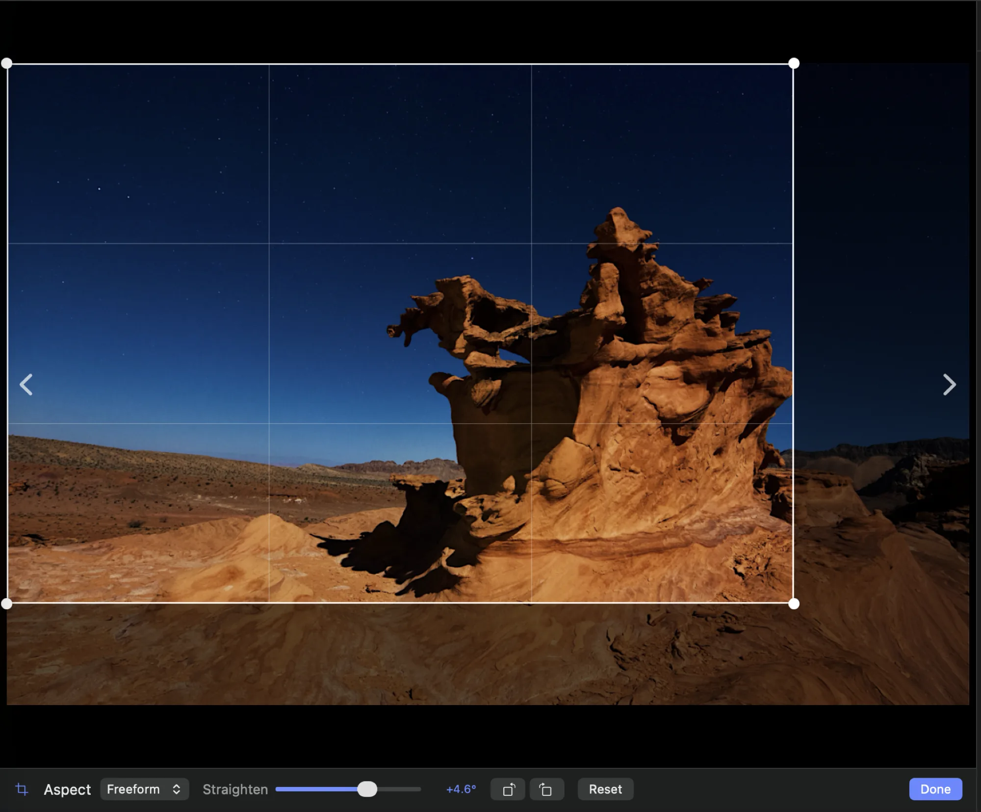 Crop mode over a moonlit sandstone formation: a crop rectangle with round corner handles and a thirds grid, the area outside it dimmed. The tray below shows an Aspect menu set to Freeform, a Straighten slider reading plus 4.6 degrees, rotate-left and rotate-right buttons, Reset, and Done. The straightened frame has scaled to cover, so no blank corners appear.